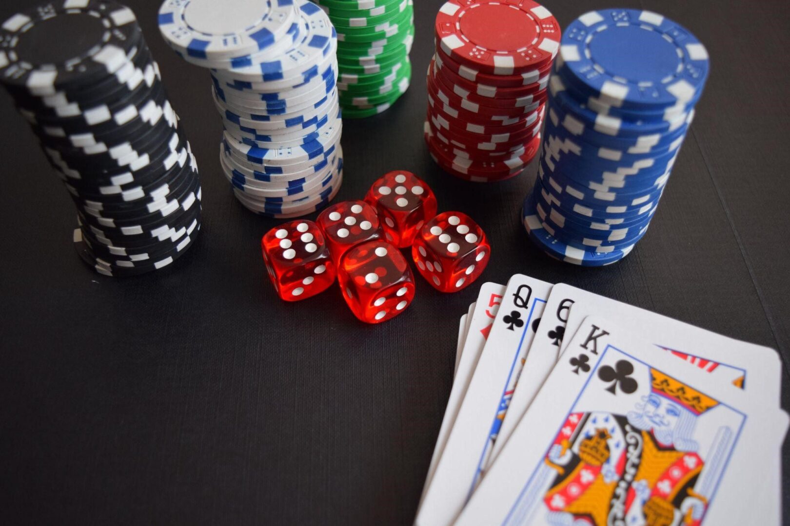 An image of a deck of cards, poker chips and five dice.