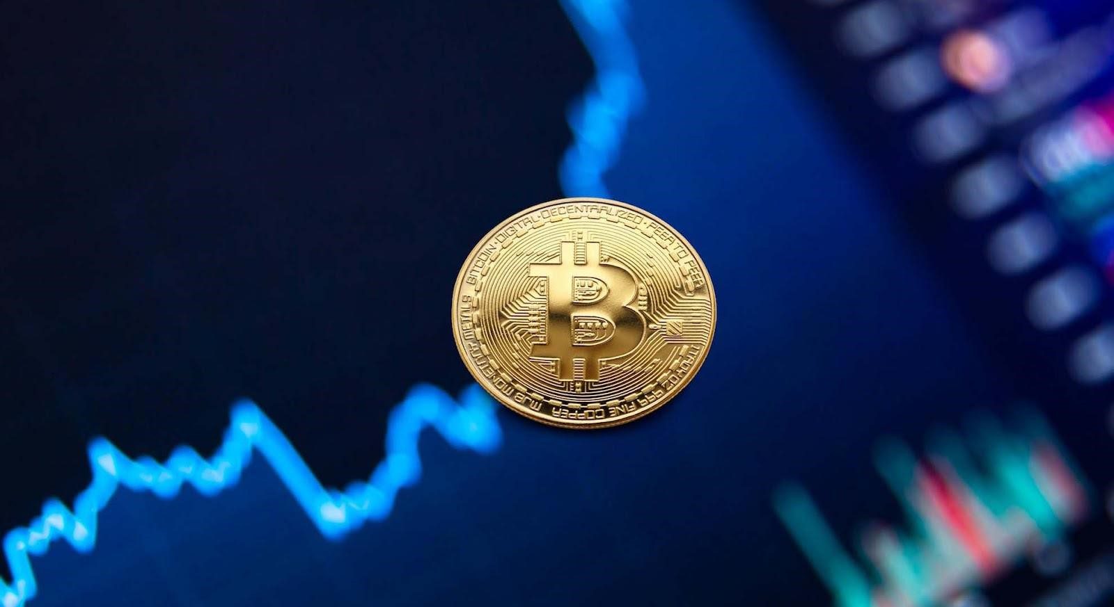 An image of a gold coin with the bitcoin logo on it with a graph in the background