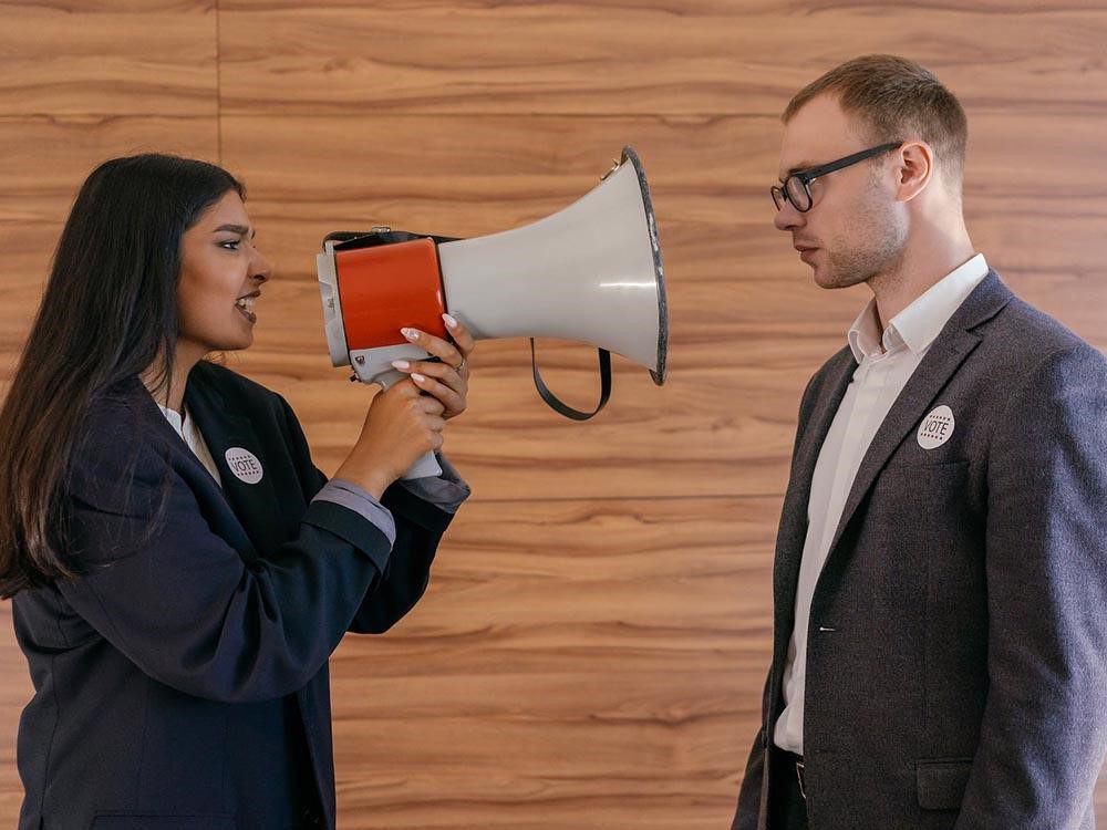 A woman talking in a megaphone to a guy next to her