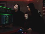 Three persons with masks infront a computer